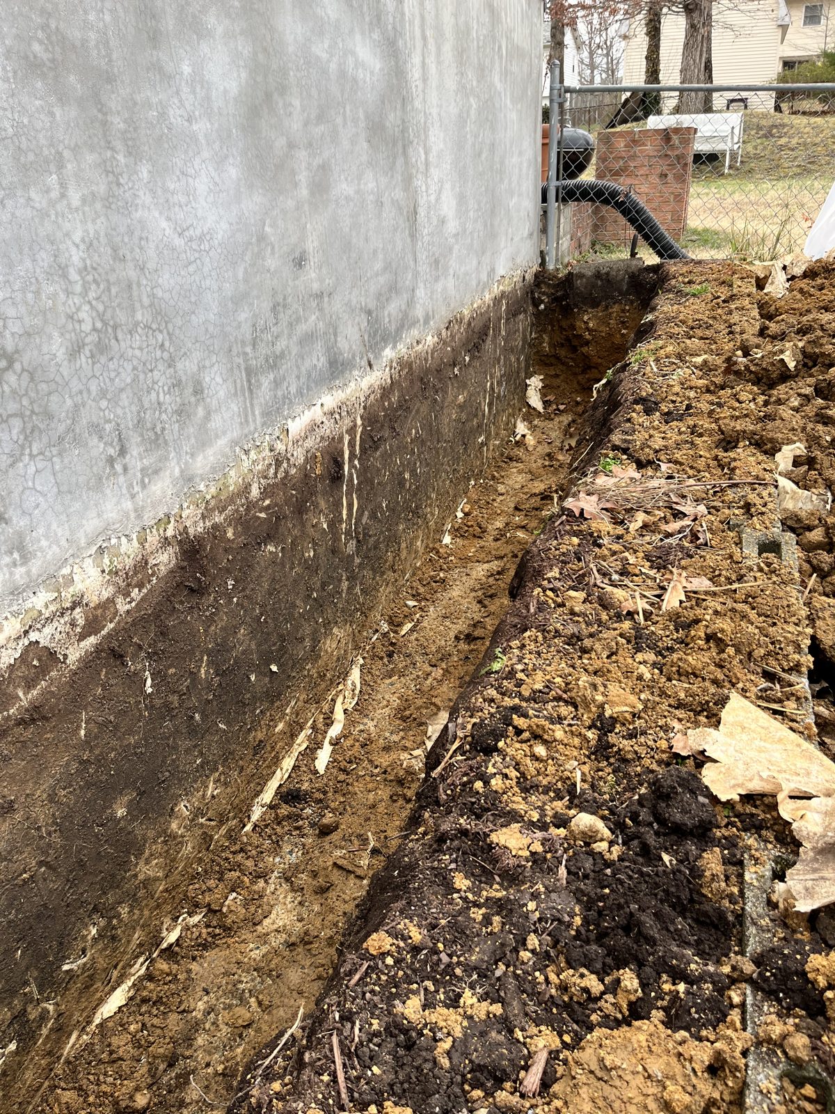 Trench excavated along the foundation wall, exposing the concrete